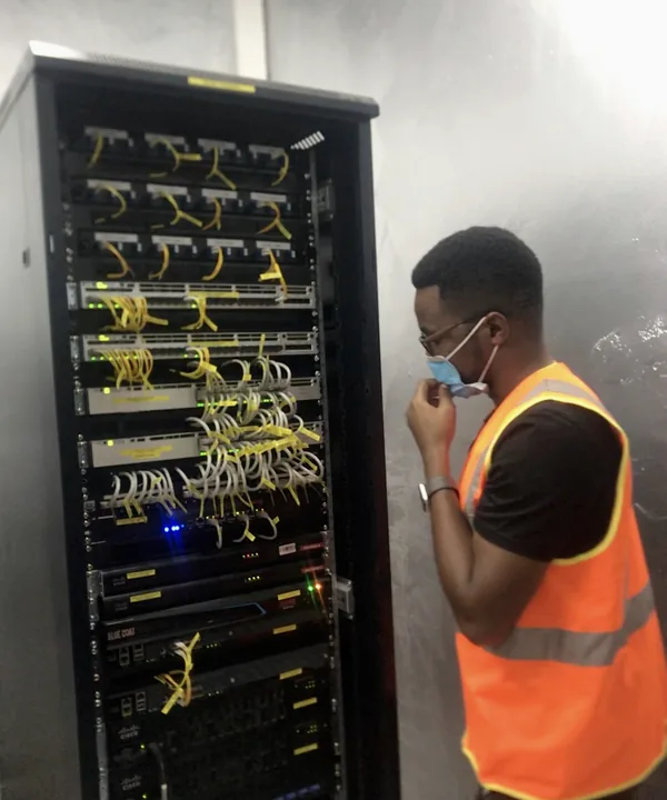 TwinBytes engineer reviewing a live network rack on site in Kigali